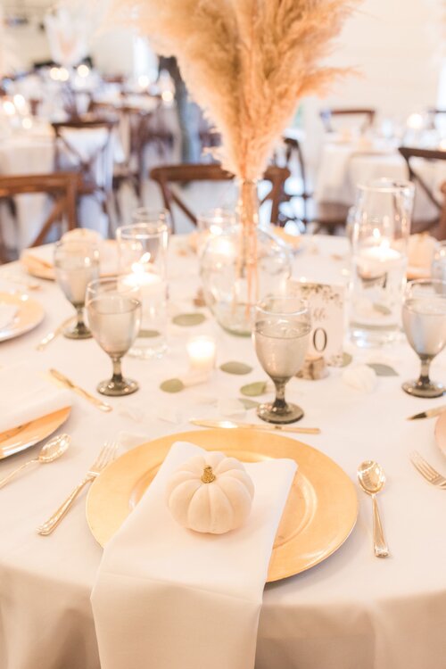 gold and white wedding reception place settings with pampas grass centerpiece