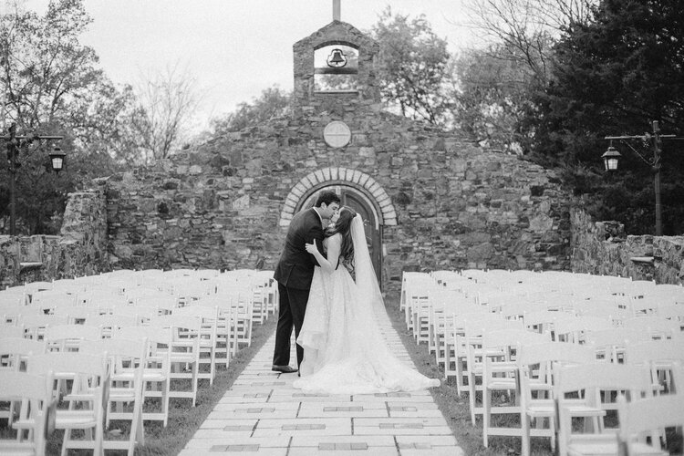 bride and groom kissing in front of stone arch