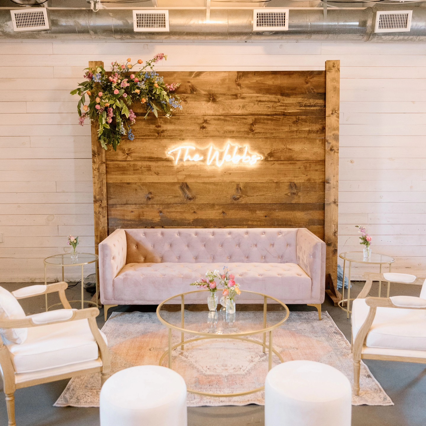 pink and white wedding reception sitting area with wooden backdrop and neon sign