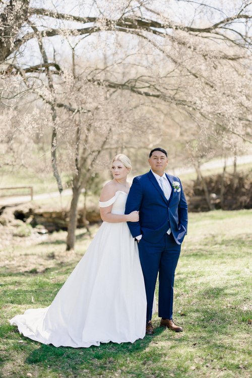 bride and groom under budding tree