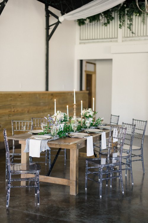 wooden wedding reception table with clear chairs