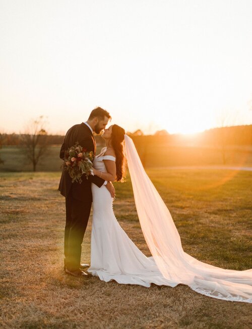 bride and groom kissing at sunset
