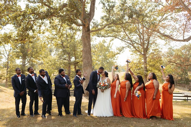 bride and groom kissing while wedding party cheers